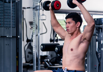 Close up of Muscular bodybuilder guy doing exercises with dumbbells.Young male fitness model lifting weights ,shirtless powerful and strong sporty in sport gym.Sports muscle for health care concept.