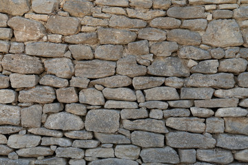 Old gray wall made of large and small rectangular hewn natural stones
