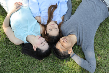 up side down image of happy asian family closing eyes and happy smiling face while lying on the green grass filed in nature during summer time