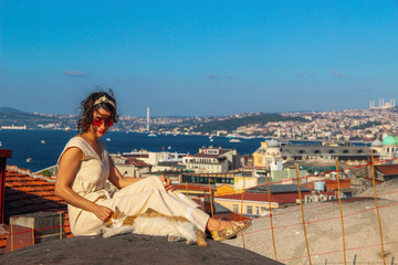 Fototapeta na wymiar Woman touching yellow cat at the roof with bosphorus background in Istanbul