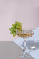 Beautiful crystal glass with champagne and green grapes fashion minimalistyc geometric composition