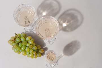 Beautiful crystal champagne glasses with green grapes grey minimalistic background  with space for design
