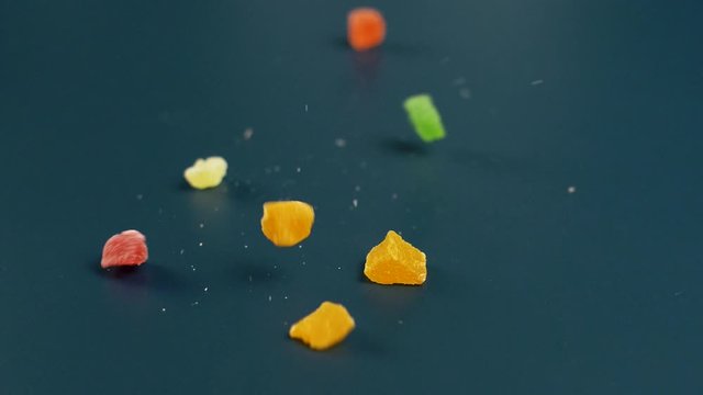 Nice sweet jelly candy with shugar falling in slow motion on dark surface. Close up of colour food.