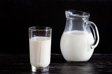 Milk in glass jug on the black background