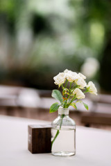 Excellent buttercup flowers in glass vase on dining wooden table with garden.