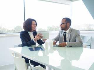 Female mentor training male newcomer. Focused business man and woman sitting at meeting table,...