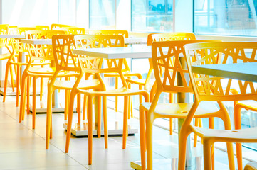 Modern yellow color chairs in furnished interior.  Side view of restaurant with blue glass filter. 