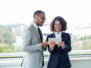 Two cheerful colleagues discussing team project during work break. Happy business man and woman...