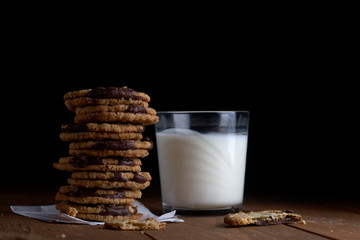 a stack of cookies with chocolate and a glass of milk