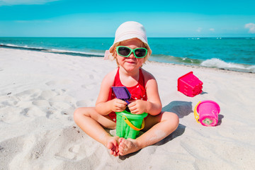 cute little girl play with sand on beach