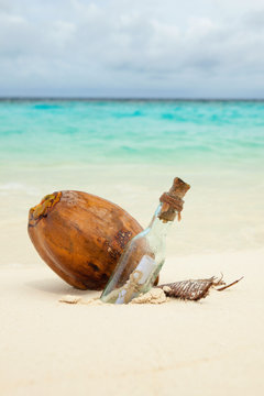 A letter in a bottle and coconut on the beach. Island lifestyle. White sand, crystal-blue sea of tropical beach. Ocean beach relax, travel to islands