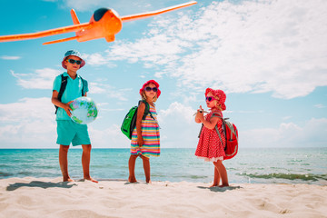 kids travel on beach, boy and girls with globe, toy plane and binoculars