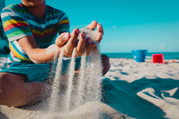 boy play with sand on beach vacation, kids summer fun at sea