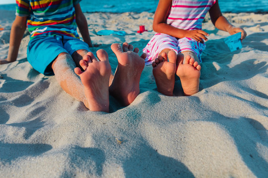 feet on kids- boy and girl -play with sand on beach