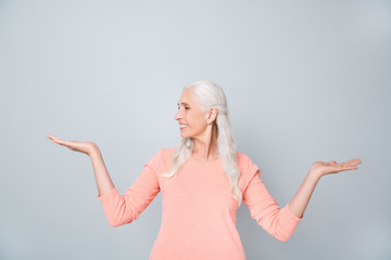 Photo of turning to the side smart granny lady trying to make right choice between two variants isolated grey background