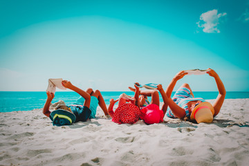 family with kids reading books at beach
