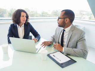 Business partners watching presentation and discussing project. Business man and woman sitting at...