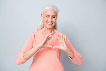 Close up photo of sincere honest friendly and kind granny making small heart near breast isolated...