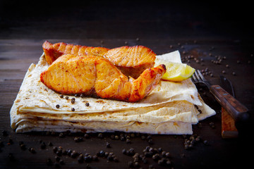 Fried sea trout, lemon and sauce. Grill dishes, seafood or fish and pita for the restaurant menu. Wooden background.