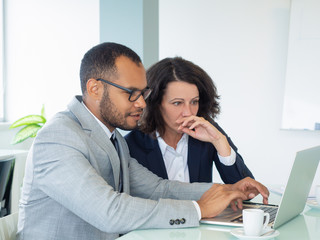 Successful professional team watching presentation on laptop. Business man and woman sitting at...