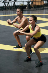 Obraz na płótnie Canvas Sport people exercising, doing squat exercise workout outdoors