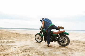 Fototapeta na wymiar Handsome man biker on his bike outdoors on a beach in helmet.