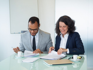 Businesspeople signing agreement. Business man and woman sitting at meeting table, reading and signing document. Teamwork concept
