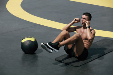 Fitness workout. Man doing abs sitting crunch exercise at street