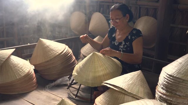 Old vietnamese woman teaching her great-granddaughter to make conical hats