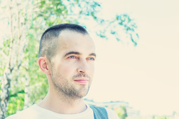 Attractive young man in Park in summer, look aside, portrait, close up, toned