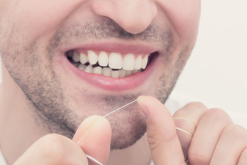 Young guy uses dental floss, cropped image, close up, toned