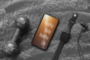 Fitness healthy lifestyle mockup smartphone concept. Healthy Body Healthy Life quote on mobile phone with dumbbells,smart watch, earphone. Mock up mobilephone for fitness healthy concept.