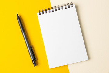 Notebook on a black spiral with white sheets on a colorful background. The concept of education, writing down ideas, plans. Place for text. Minimalism, flat lay.