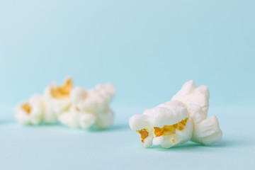 Close-up popcorn on a pastel blue background. Unhealthy diet concept. Minimalism, flat lay, top view, place for text.