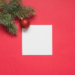 Fototapeta na wymiar Christmas evergreen branches and red ball on red. View from above, flat lay. Xmas holiday. Template, mockup, greeting New Year card.