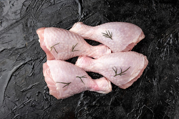 Raw chicken legs on black background.