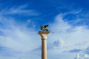 Saint Mark Winged Lion medieval statue, a symbol of the Old Venice Republic, at the top of an ancient column among clouds