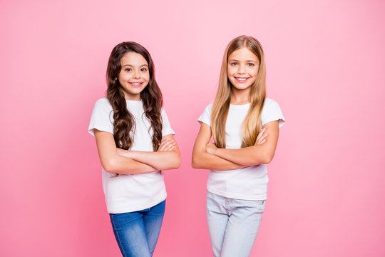 Photo of successful little children girls being photographed over pink background wearing jeans denim with arms crossed