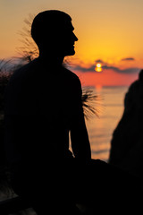 the concept of tourism, recreation-a happy man overlooking the sea and the sunset. silhouette of the people