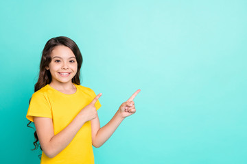 Photo of nice cute smiling girl pointing at emptiness to the left above while isolated with...