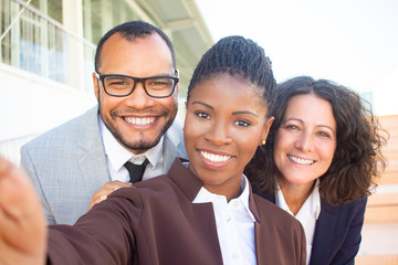 Happy black businesswoman taking group selfie with team. Self portrait of successful multiethnic business man and women. Collective selfie concept