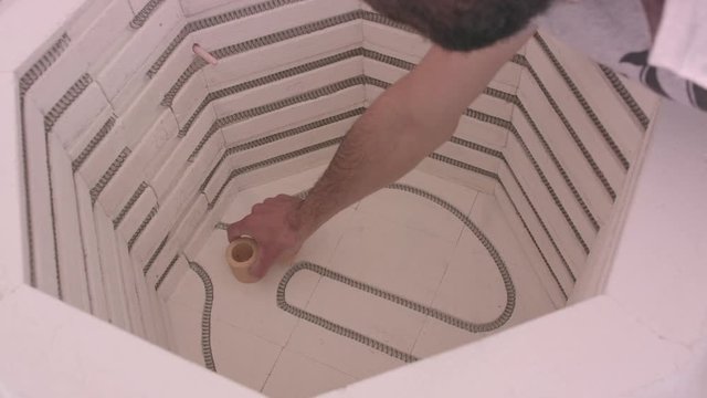 Male potter putting clay plates in a electric kiln. Clay plates making. Electric oven for ceramic clay products, kiln for dishware. Fire the plates clay in a kiln