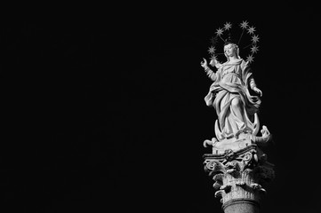 Statue of Virgin Mary of the Stars crushing dragon and crescent at the top of an ancient column in...