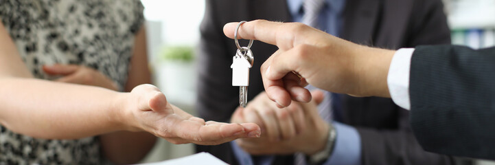 Hand of realtor hold house key aganist office background. Family new apartment credit concept.