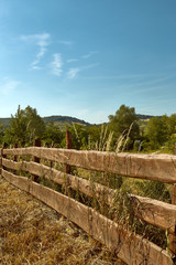Fototapeta na wymiar Close view on old wooden fence in a countryside in a summer time with clear sky