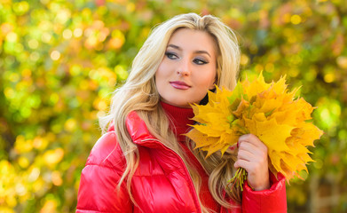 Woman spend pleasant time in autumnal park. Lady posing with leaves autumnal nature background. Girl blonde makeup dreamy face hold bunch fallen maple yellow leaves. Autumnal bouquet concept