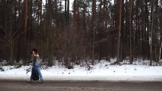 Sporty girl engaged in Nordic walking. Girl walking through the woods with Scandinavian sticks. A young woman walks in the woods in winter with Scandinavian sticks.