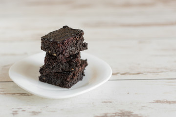 A stack of chocolate brownies on wooden background, homemade bakery and dessert.