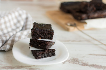 A stack of chocolate brownies on wooden background, homemade bakery and dessert.