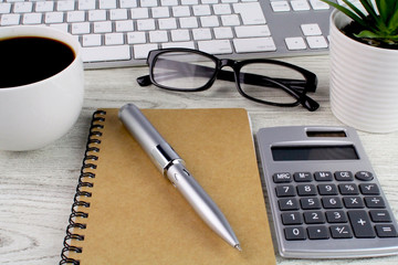 White wooden table office desk with computer,keyboard,smart phone,calculator,notebook